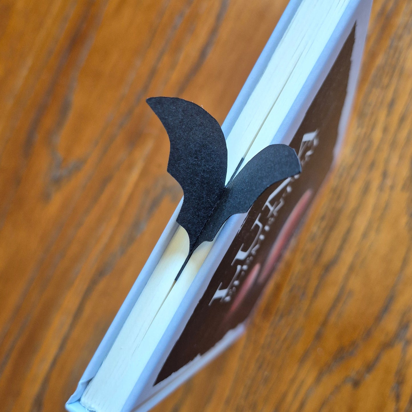 Nårbilde av flaggermus-bokmerke, med vinger som brer seg ut over toppen av boken.